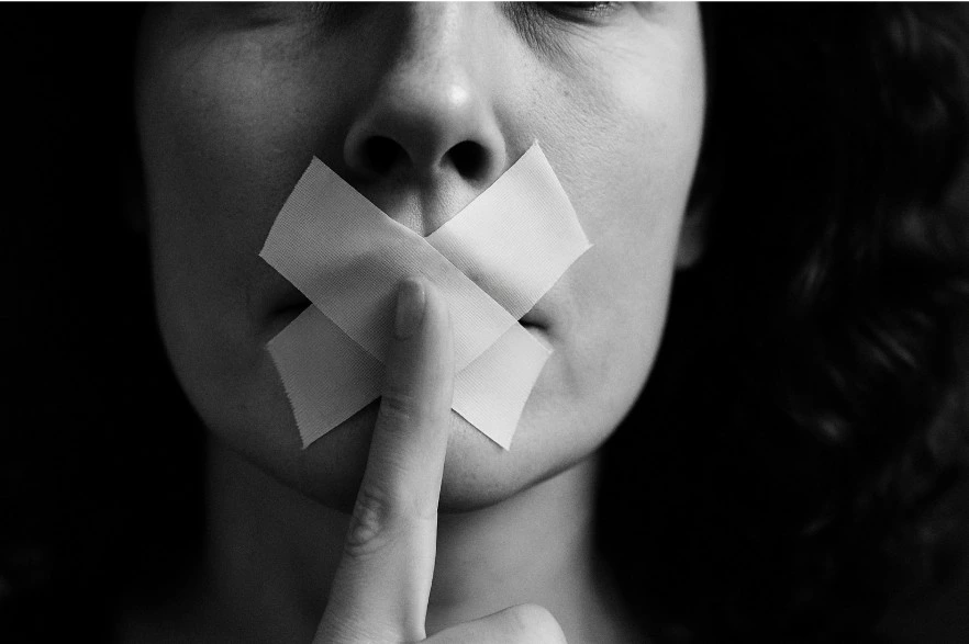 Mujer con esparadramo en la boca y haciendo el gesto de silencio