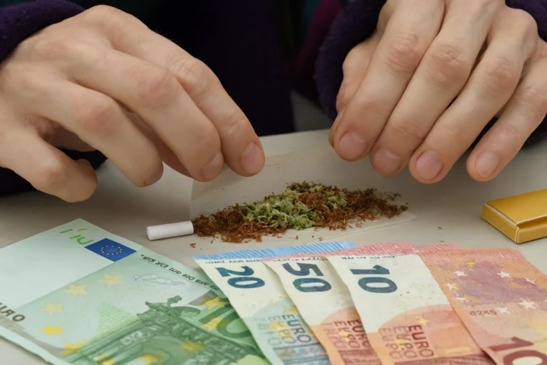 Una persona mezclando tabaco y hierba con billetes